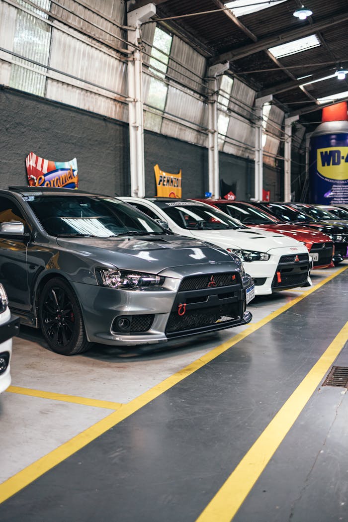 A lineup of stylish cars displayed indoors at a vibrant car show, highlighting modern automotive design.