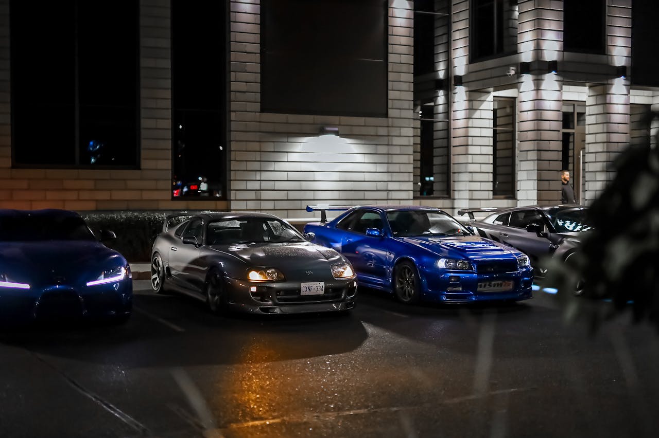 Line of luxury sports cars parked at night in urban setting, highlighting modern elegance.